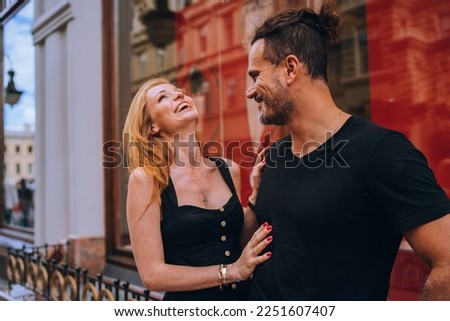 Young redhead European woman laughing touching boyfriend outdoors. Handsome Hispanic  man dating with girl on valentine's day. Pretty American girl giggling after fiancé’s joke. Romance, honeymoon.
