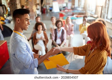 Young Redhead Female Congratulate To A Student For Successful Attending Business Seminar, Giving Him Certificate In Folder. Selective Focus Image.