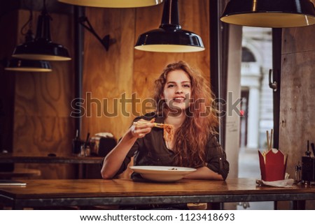 Young redhead female eating spicy noodles in an Asian restaurant. 