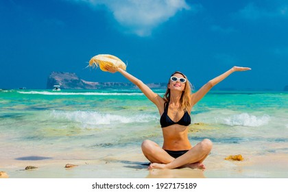 Junge Rotkopfmädchen in schwarzem Bikini und mit Hut auf Balos Strand, West Kreta, Griechenland. Sommerurlaub, Juli