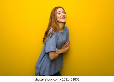 Young redhead girl over yellow wall background keeping the arms crossed while smiling - Shutterstock ID 1311481832