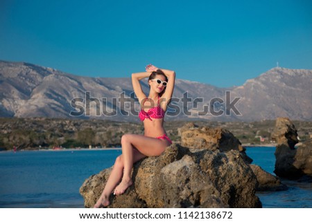 Young redhead girl in sunglasses and bikini on Elafonissi beach, west Crete, Greece. Summertime season