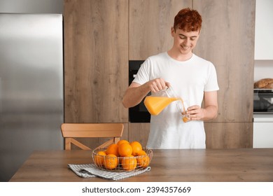 Young redhead man pouring orange juice into glass in kitchen - Powered by Shutterstock