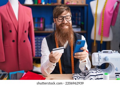 Young Redhead Man Tailor Using Smartphone And Credit Card At Clothing Factory
