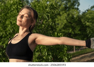 A young redhead stretches out her arms and closes her eyes, enjoying the wellbeing after an outdoor yoga-Pilates class. The sun and tranquility surround her on a perfect day. - Powered by Shutterstock