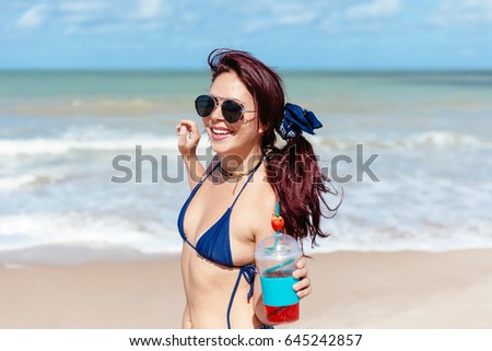 Young redhead woman drinking strawberry cocktail on the beach