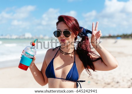 Young redhead woman drinking strawberry cocktail on the beach