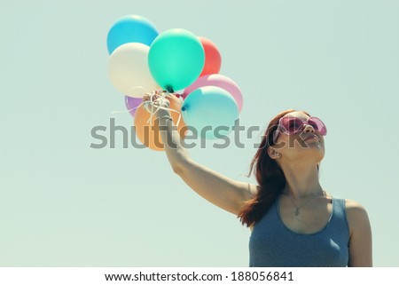 Young redhead woman holding colorful balloons