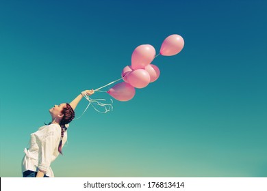 Young redhead woman holding pink balloons
