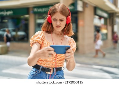 Young Redhead Woman Playing Video Game At Street