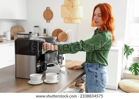 Young redhead woman preparing coffee in kitchen at home