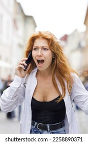 Young redhead woman shouting on the phone in stress dealing with some problems. - Shutterstock ID 2258890371