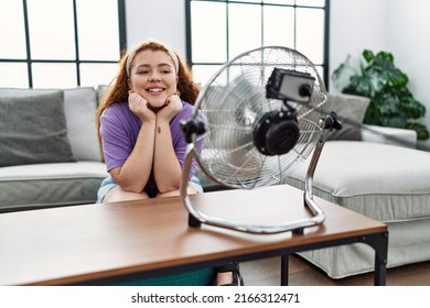 Young redhead woman smiling confident using electric ventilator at home