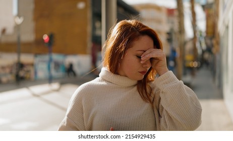 Young redhead woman stressed standing at street