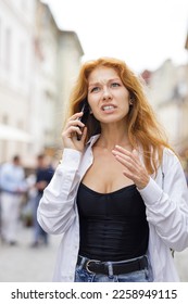 Young redhead woman talking on the phone with anger and stress solving some problems. - Shutterstock ID 2258949115