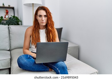 Young Redhead Woman Using Laptop At Home Thinking Attitude And Sober Expression Looking Self Confident 
