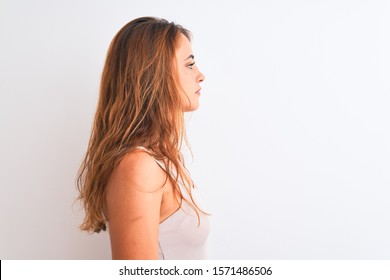 Young redhead woman wearing casual t-shirt stading over white isolated background looking to side, relax profile pose with natural face with confident smile.