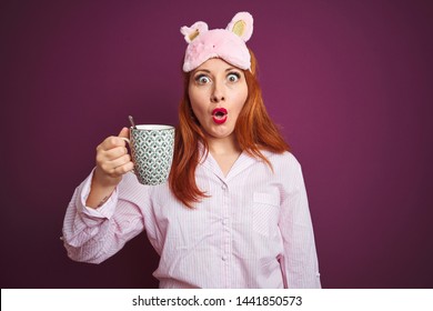 Young redhead woman wearing pajama drinking coffee over purple isolated background scared in shock with a surprise face, afraid and excited with fear expression - Powered by Shutterstock