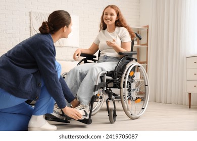 Young redhead woman in wheelchair with nurse at home - Powered by Shutterstock