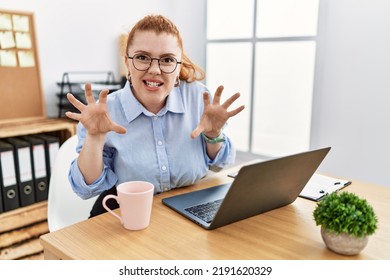 Young Redhead Woman Working At The Office Using Computer Laptop Smiling Funny Doing Claw Gesture As Cat, Aggressive And Sexy Expression 