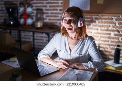 Young Redhead Woman Working At The Office At Night Wearing Headphones Celebrating Crazy And Amazed For Success With Open Eyes Screaming Excited. 