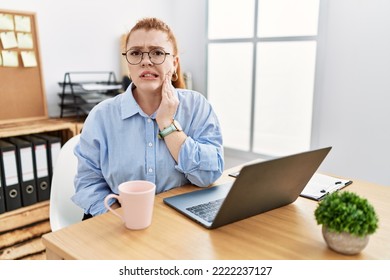 Young Redhead Woman Working At The Office Using Computer Laptop Touching Mouth With Hand With Painful Expression Because Of Toothache Or Dental Illness On Teeth. Dentist 