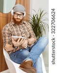 Young redheaded hipster using his tablet while sitting on chair