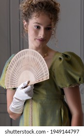 A Young Regency Woman Wearing A Shot Silk Dress And Holding A Fan