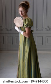 A Young Regency Woman Wearing A Shot Silk Dress And Holding A Fan