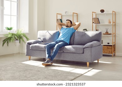 Young relaxed man sitting on comfortable couch in the living room at modern home and having a rest from a work with closed eyes. Calm peaceful guy enjoying quiet time alone in the room and dreaming. - Powered by Shutterstock