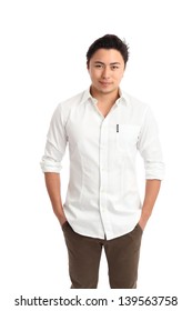 Young Relaxed Man Standing With His Hands In His Pockets, Wearing A White Shirt And Brown Pants. White Background.