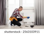 Young repairman contractor repairing heating panel