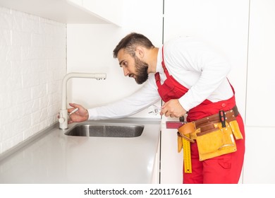 Young Repairman Installing Faucet Of Kitchen Sink In Kitchen Room