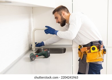 Young Repairman Installing Faucet Of Kitchen Sink In Kitchen Room