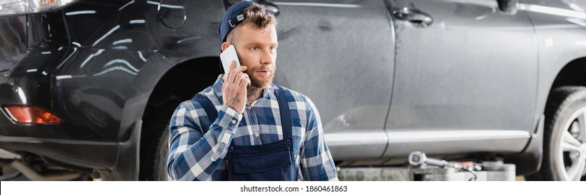 Young Repairman Talking On Mobile Phone In Workshop Near Car, Banner