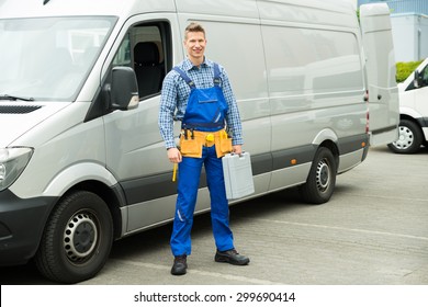 Young Repairman With Tools And Toolbox Standing In Front Of Service Van