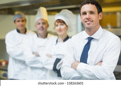 Young restaurant manager posing in front of team in restaurant 