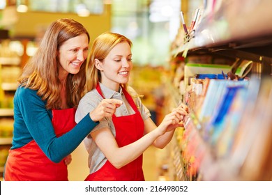 Young Retal Saleswoman Trainee In Supermarket Getting Help From Staff