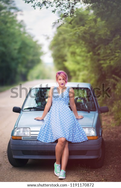 Young retro
woman sitting on hood of retro
car