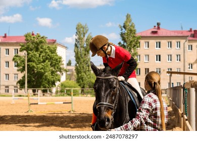 Young rider adjusts on horse with instructor's help in riding arena. - Powered by Shutterstock