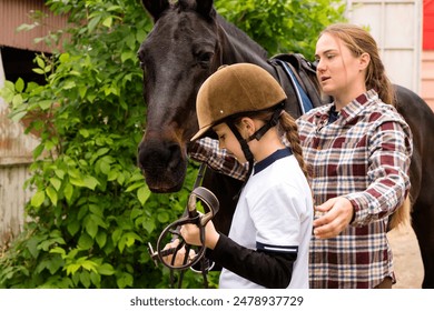 Young rider girl assisting with bridle adjustment on a horse outdoors. Equestrian equipment - Powered by Shutterstock