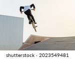 A young rider on a BMX bike does tricks in the air. BMX freestyle in a skate park.