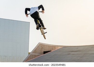 A young rider on a BMX bike does tricks in the air. BMX freestyle in a skate park.