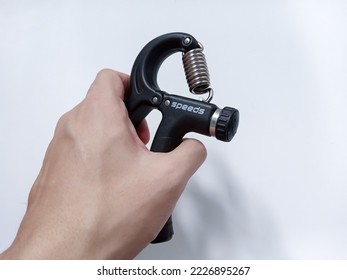 Young Man’s Right Hand Gripping Hand Exercise Gripper Isolated On White Backgrounnd. Men Right Hand Squeeze The Muscle Training Grip
