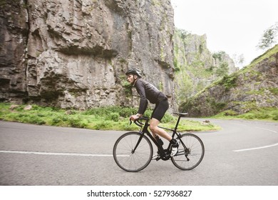 A Young Road Cyclist Dressed In Black, Attacking The Climb In Cheddar Gorge, U.K