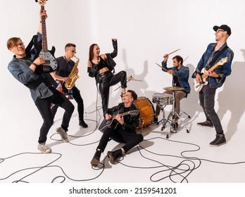 A Young Rock Band Of Six People Emotionally Playing And Singing On A White Background