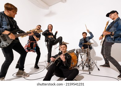 A Young Rock Band Of Six People Playing And Singing On A White Background. Close Up