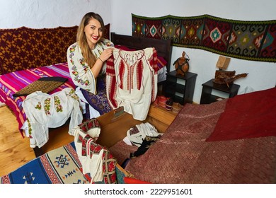 Young Romanian woman opening the wedding chest with many traditional costumes to try on