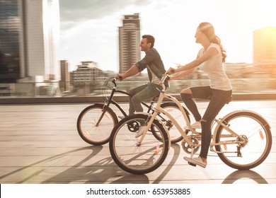 Young Romantic Couple Is Cycling In The City On The Sunset