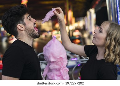 A Young Romantic Couple Eating Cotton Candy And Having Fun At An Amusement Par